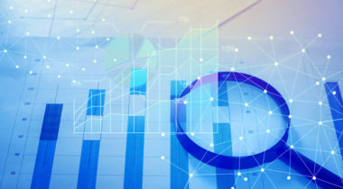 Magnifying glass and documents with analytics data lying on tableMagnifying glass and documents with analytics data lying on table